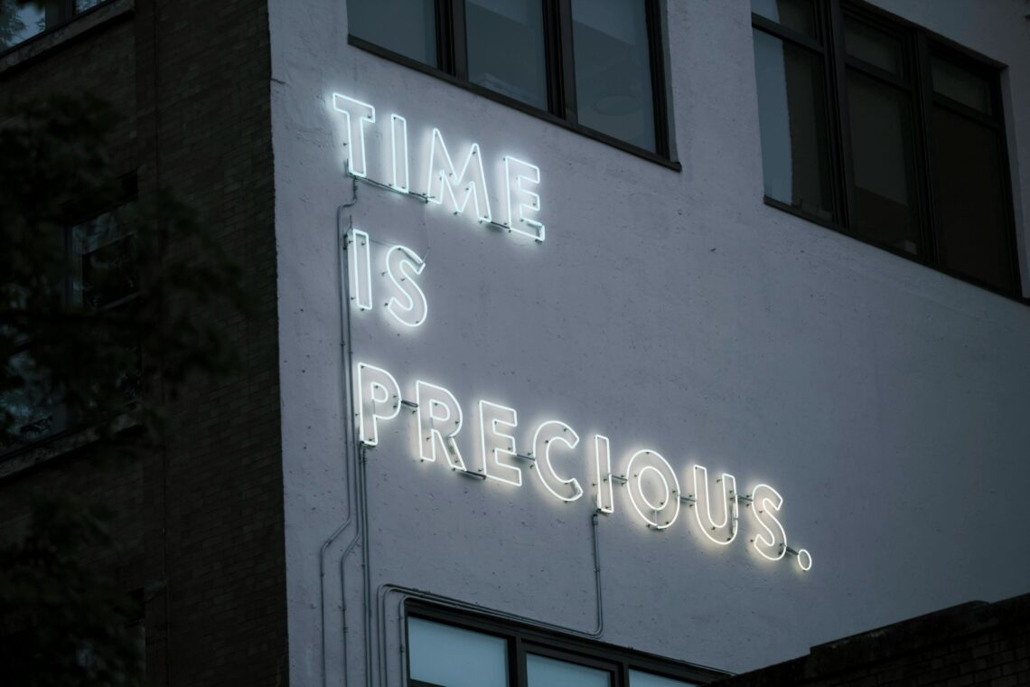 Neon sign reading 'Time is Precious' on the side of a building, reminding business owners to value their time.