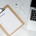 Clipboard with an 'Open Projects' checklist, pen and laptop on a marble desk, representing business admin and project tracking.