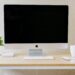 Clean, minimal desk setup with an iMac, notebook, mug and plant, showing an organised and approachable virtual assistant workspace.